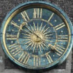 Ancient mechanical clock face with a sun design, illustrating the history of timekeeping