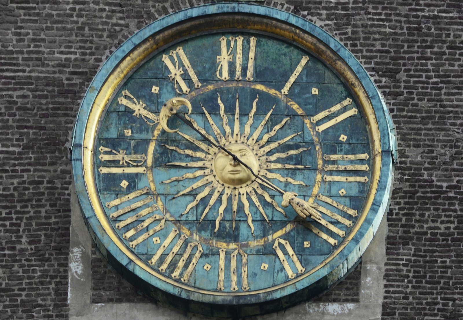 Ancient mechanical clock face with a sun design, illustrating the history of timekeeping