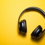 Black noise-canceling headphones on a yellow background, essential for listening to binaural beats and focus frequencies