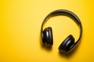 Black noise-canceling headphones on a yellow background, essential for listening to binaural beats and focus frequencies