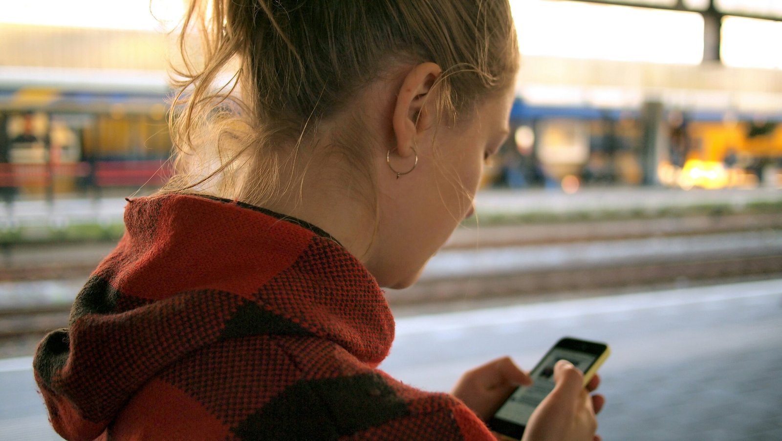 Woman scrolling on a smartphone in public, illustrating social media addiction and the need for a digital detox