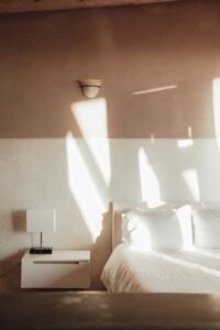 Sunlight hitting a minimalist bedroom wall in the morning, representing natural wake up cycles.