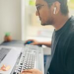 Man in deep focus wearing headphones and typing to trigger flow state.